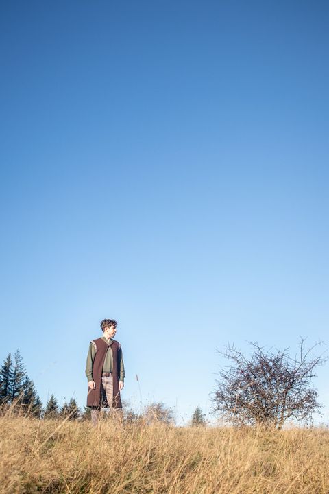 David Hughes, Edinburgh-based storyteller, standing in a wild grassy field at dusk